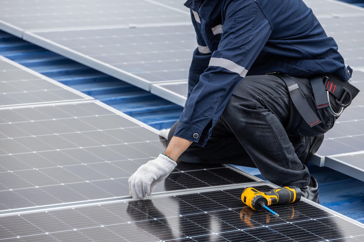 Tekniker i arbete med att montera solceller på tak – noggrann installation av solcellsanläggning med verktyg synligt i förgrunden.