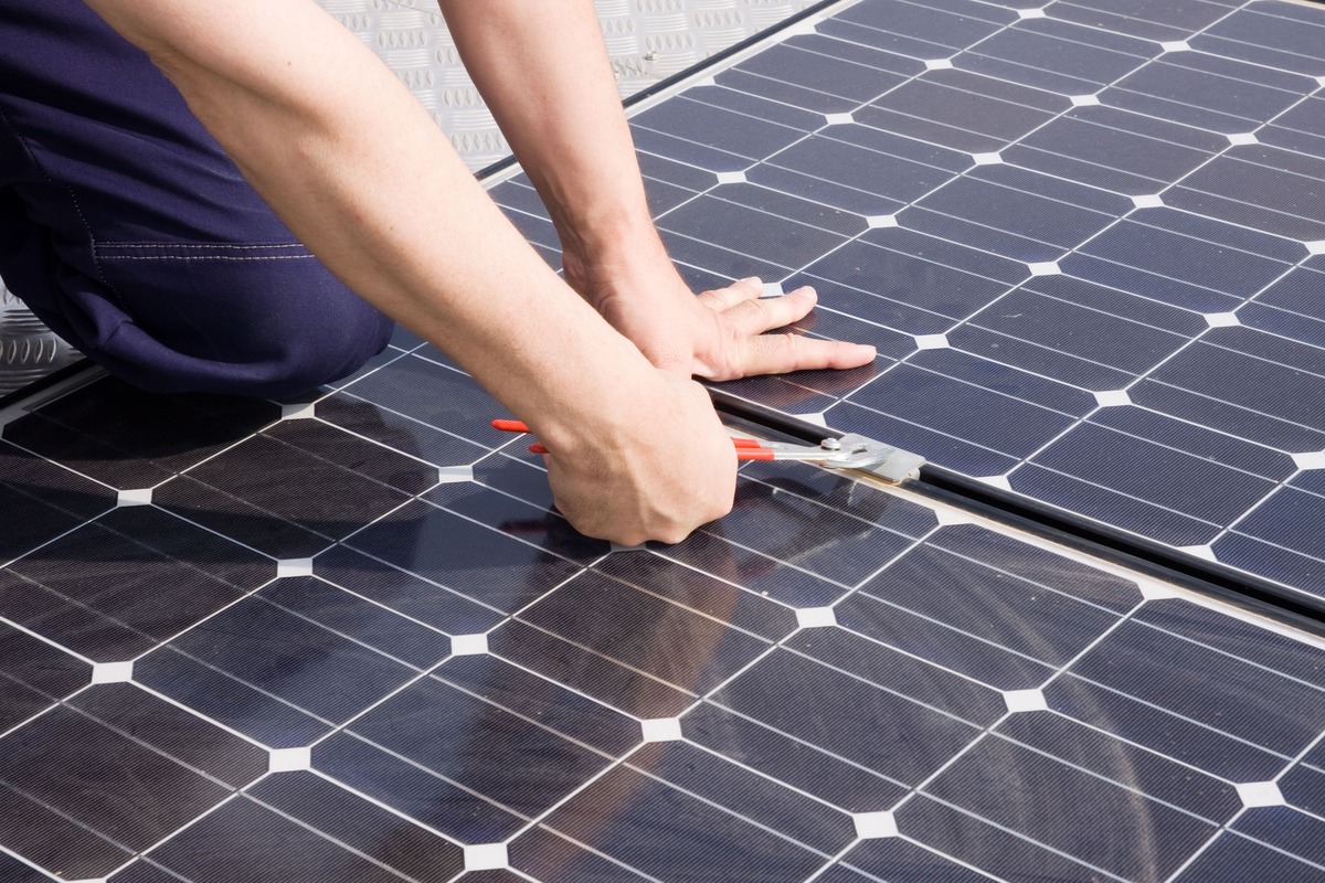 Närbild på person som monterar solpanel med handverktyg