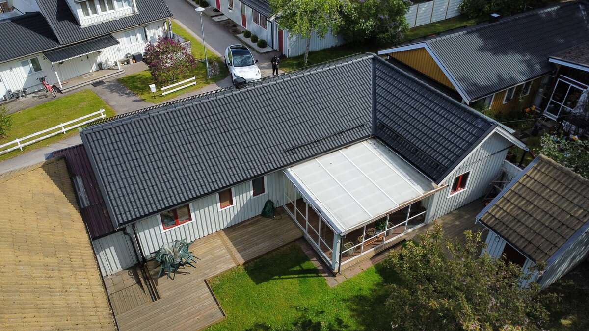Flygfoto över vit villa med nytt svart tak i takpannemönster i villaområde