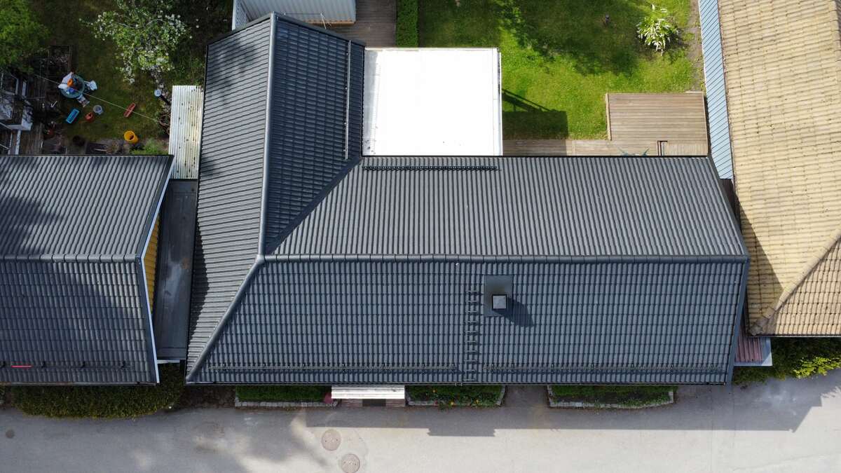 Flygfoto rakt uppifrån på hus med svart tak i takpannemönster och altantak