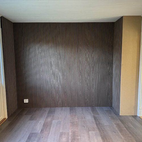 Tomt rum med mörk träpanel på fondvägg och golv i mörk träfinish.