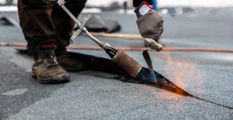 En takläggare från Vimed Tak & Bygg AB som svetsar tätskikt med gasolbrännare.