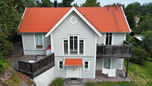 En vit villa med rött tak och balkonger fotograferad framifrån.