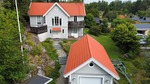 En vit villa med rött tak och ett intilliggande garage med matchande tak.