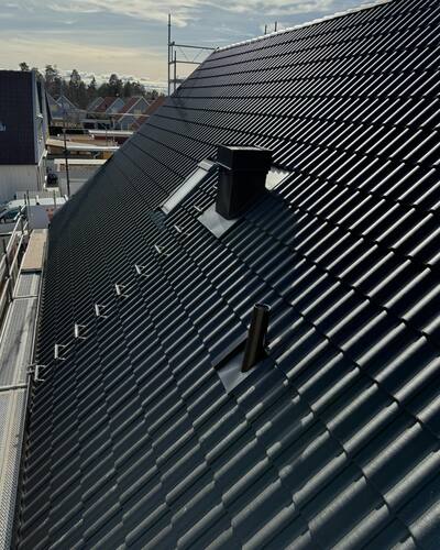 Ett svart tak med takpannor och två ventilationsrör.