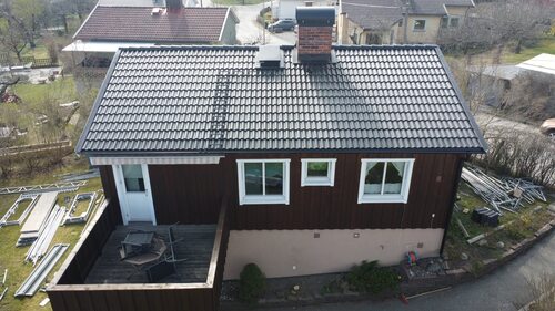 Ett mörkbrunt hus med svart tak och två skorstenar.