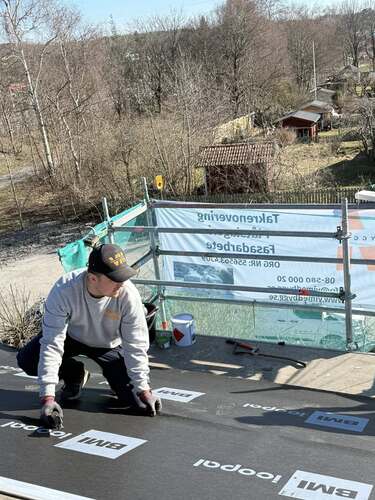 En takarbetare på Vimed Tak & Bygg AB som monterar underlagspapp på ett hustak.