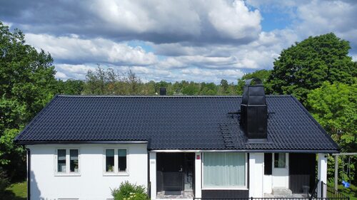 En vit villa med nylagt svart tak.