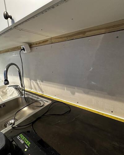 Diskbänk med avskalad vägg och verktyg i förberedelse för montering av kakel.