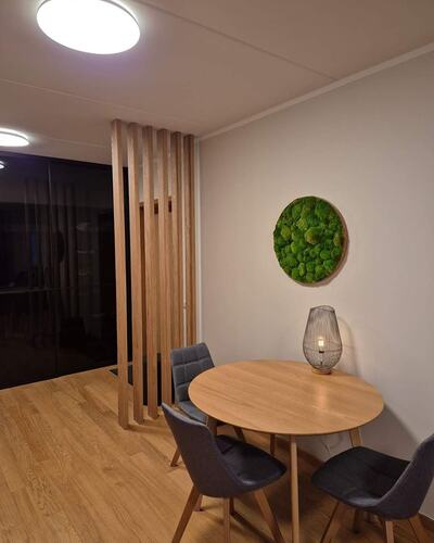 Modern matplats med rundbord, träpanel och väggdekoration i grönt