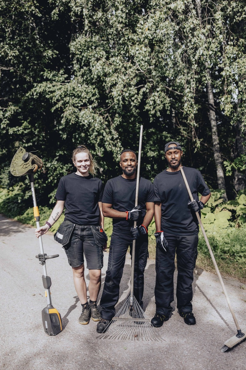 Tre personer står tillsammans utomhus med trädgårdsredskap.