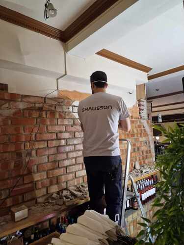 Ghalisson hantverkare utför renoveringsarbete vid tegelvägg i Stockholm