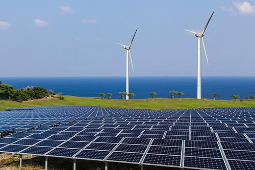 solceller med vindkraftverk i bakgrunden