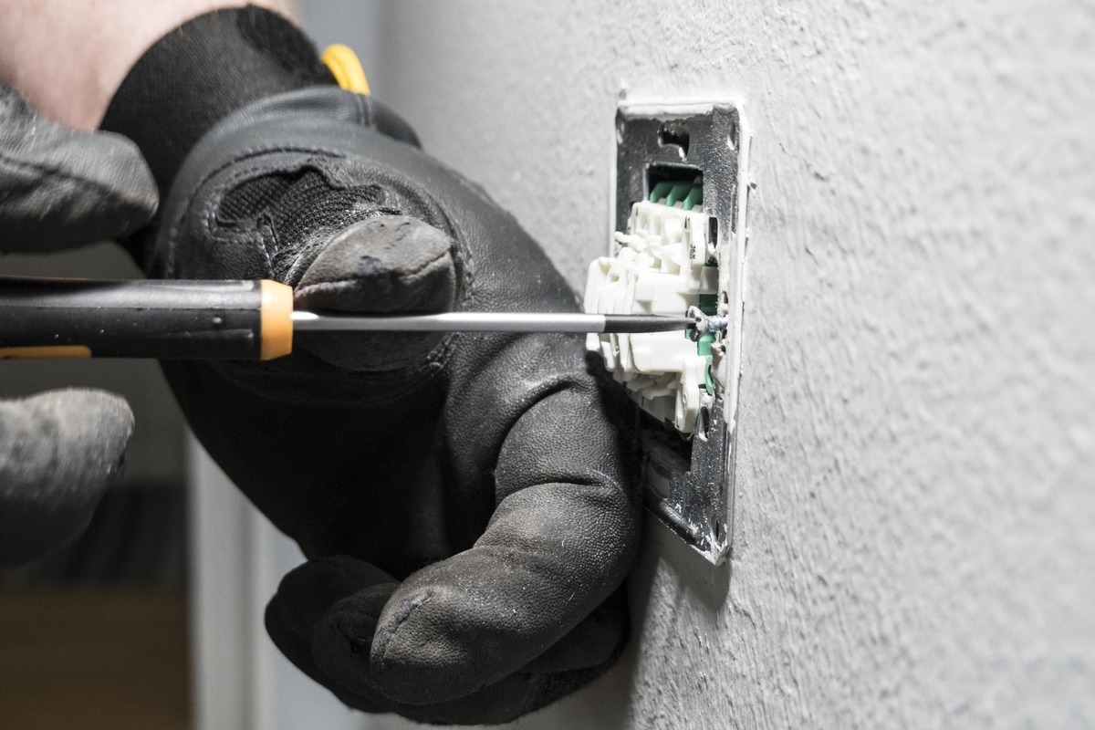 Elektriker som skruvar fast eluttag