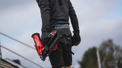 Takmontör med spikpistol och företagslogga på tröjan