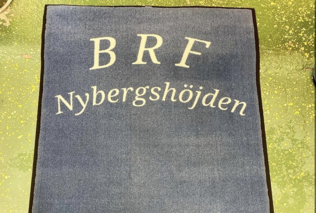 Entrématta med texten BRF Nybergshöjden i trapphusentré.