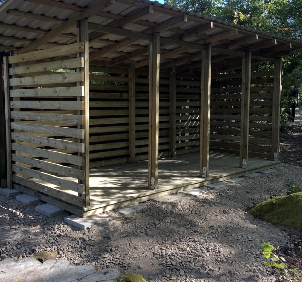 Färdigbyggd träkonstruktion med tak och väggsektioner, utförd som utomhusförråd eller vedbod.
