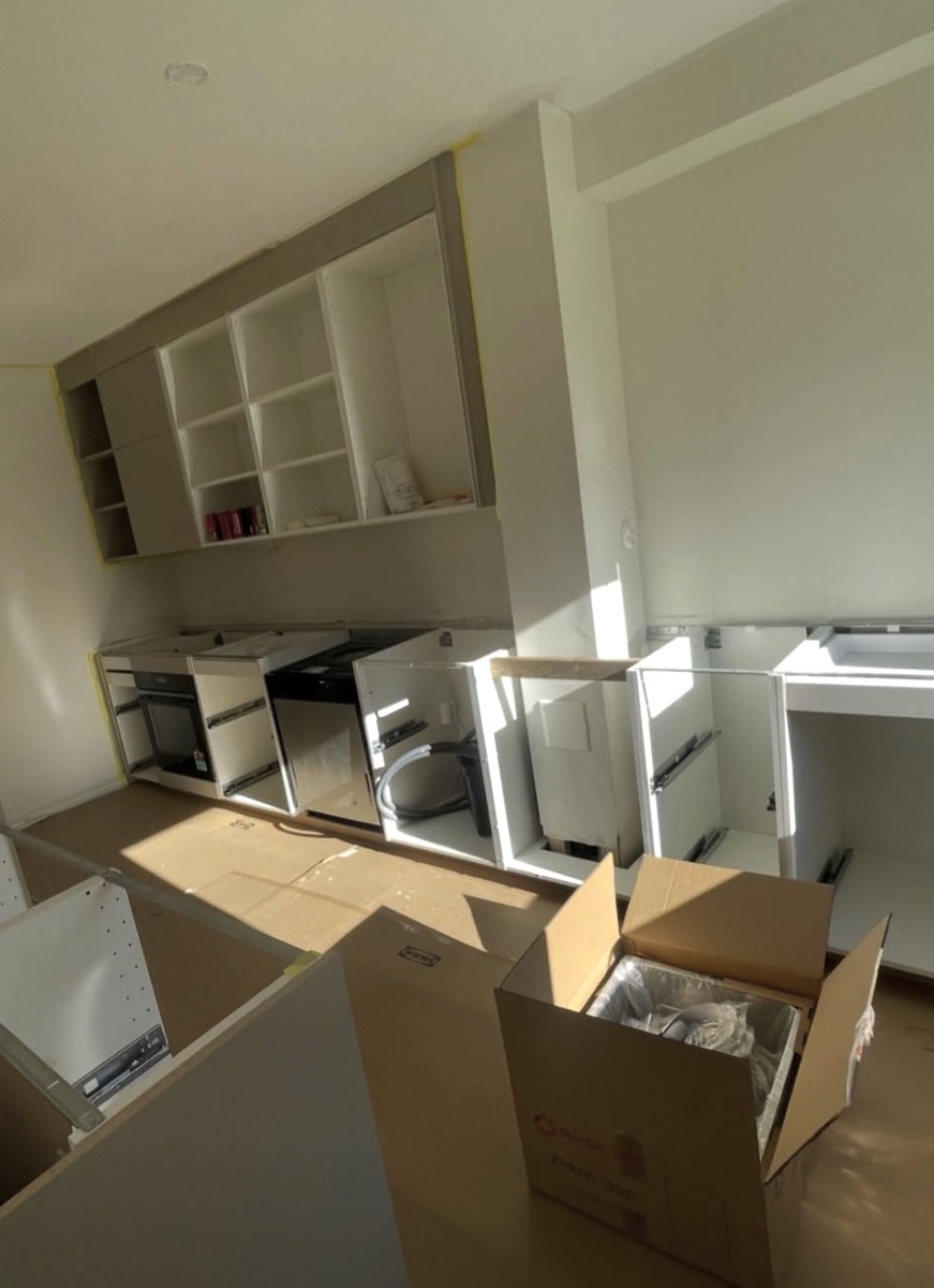 Pågående köksrenovering där stommar och skåp installeras i nytt kök.