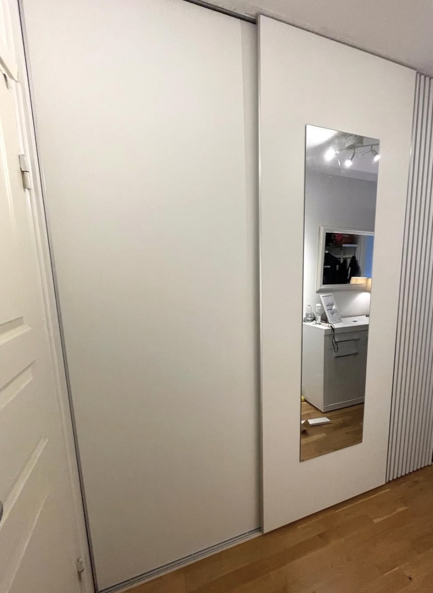 Platsbyggd garderob med skjutdörrar och integrerad spegel installerad i sovrum eller hall.
