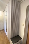 Platsbyggd hallförvaring med ribbpanel, sittbänk och integrerad spegel.