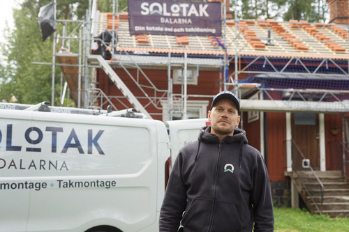 Solotak-medarbetare framför firmabil och pågående takläggning och solcellsinstallation