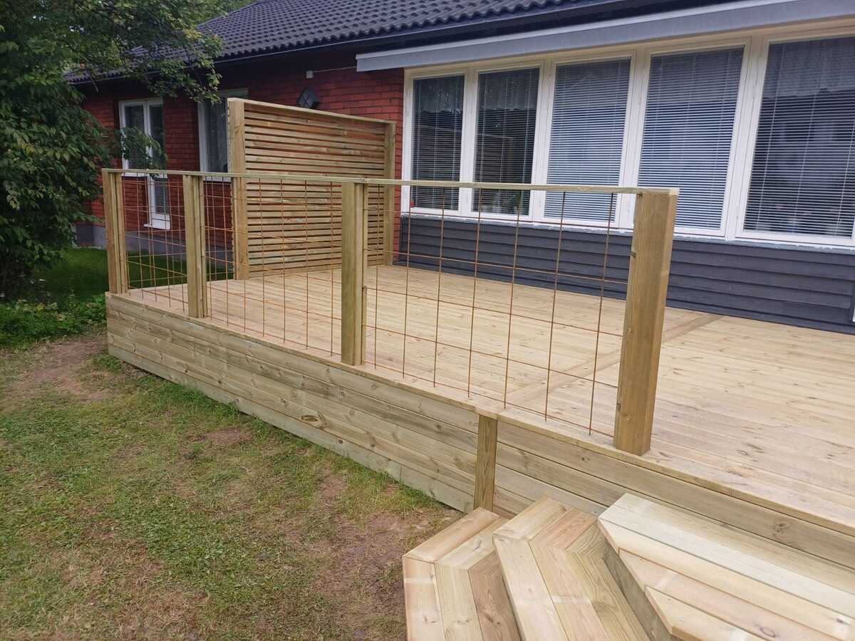 Nybyggd träaltan med räcke där markarbete och grundförberedelser har utförts intill husfasad