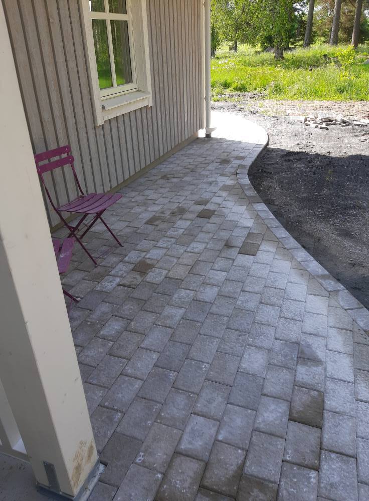 Stenlagd gång längs husfasad där markarbete och stensättning har utförts för en jämn och hållbar yta