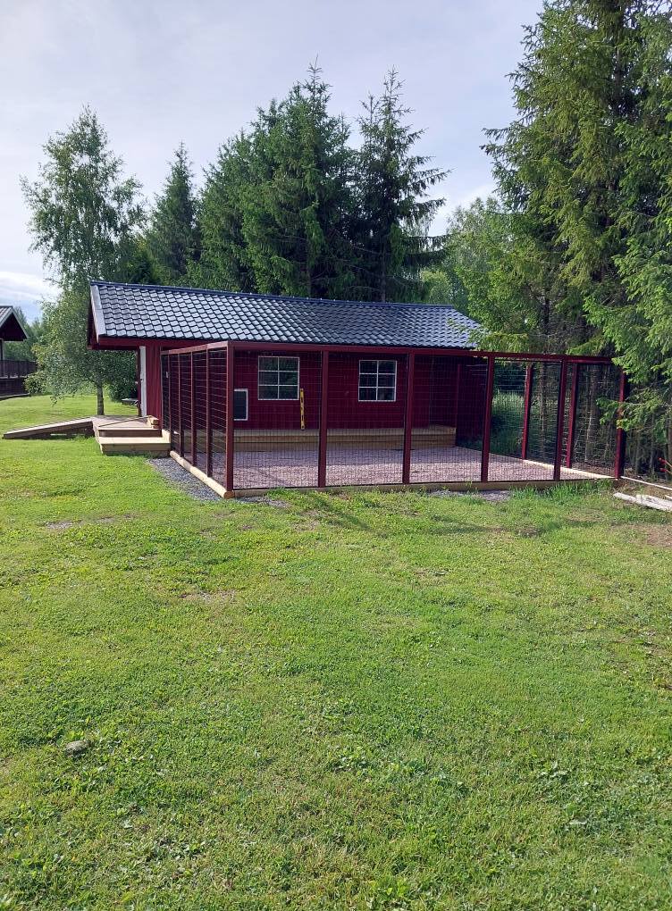 Mindre röd byggnad på grön tomt där markarbete och grundförberedelser har utförts runt huset