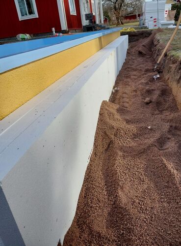 Dräneringsarbete i Hedemora längs husgrund med isolering och återfyllnad av dränerande material runt byggnaden