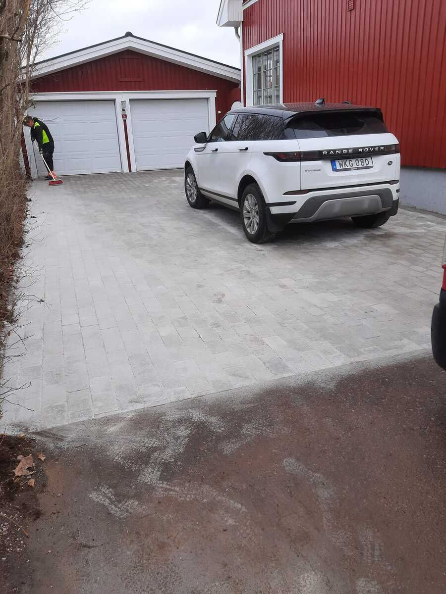 Färdig stenlagd uppfart vid garage där markarbete och sättning av marksten har utförts