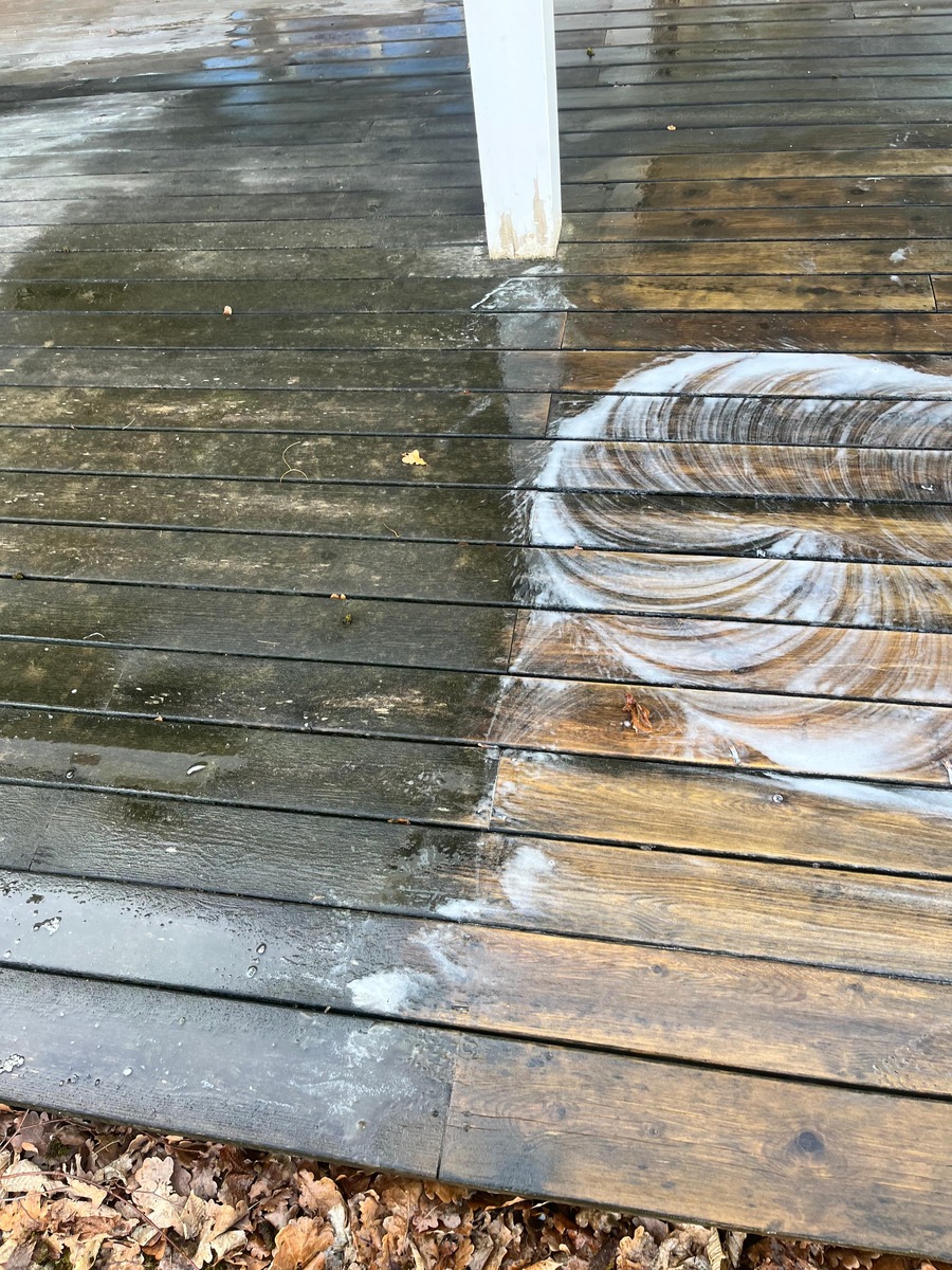 Rengöring av trätrall med borste och rengöringsmedel under golvvård utomhus.