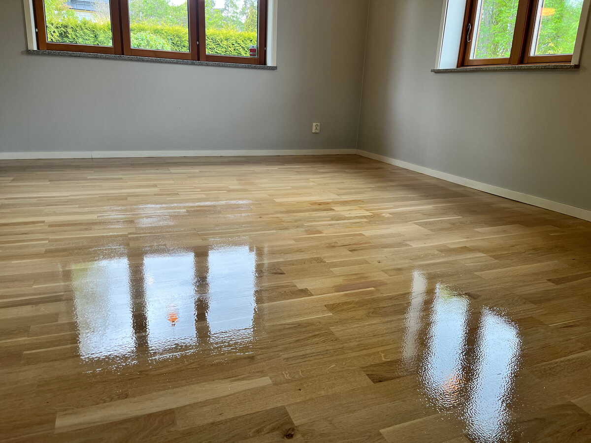 Blankbehandlat trägolv efter golvslipning i tomt rum.