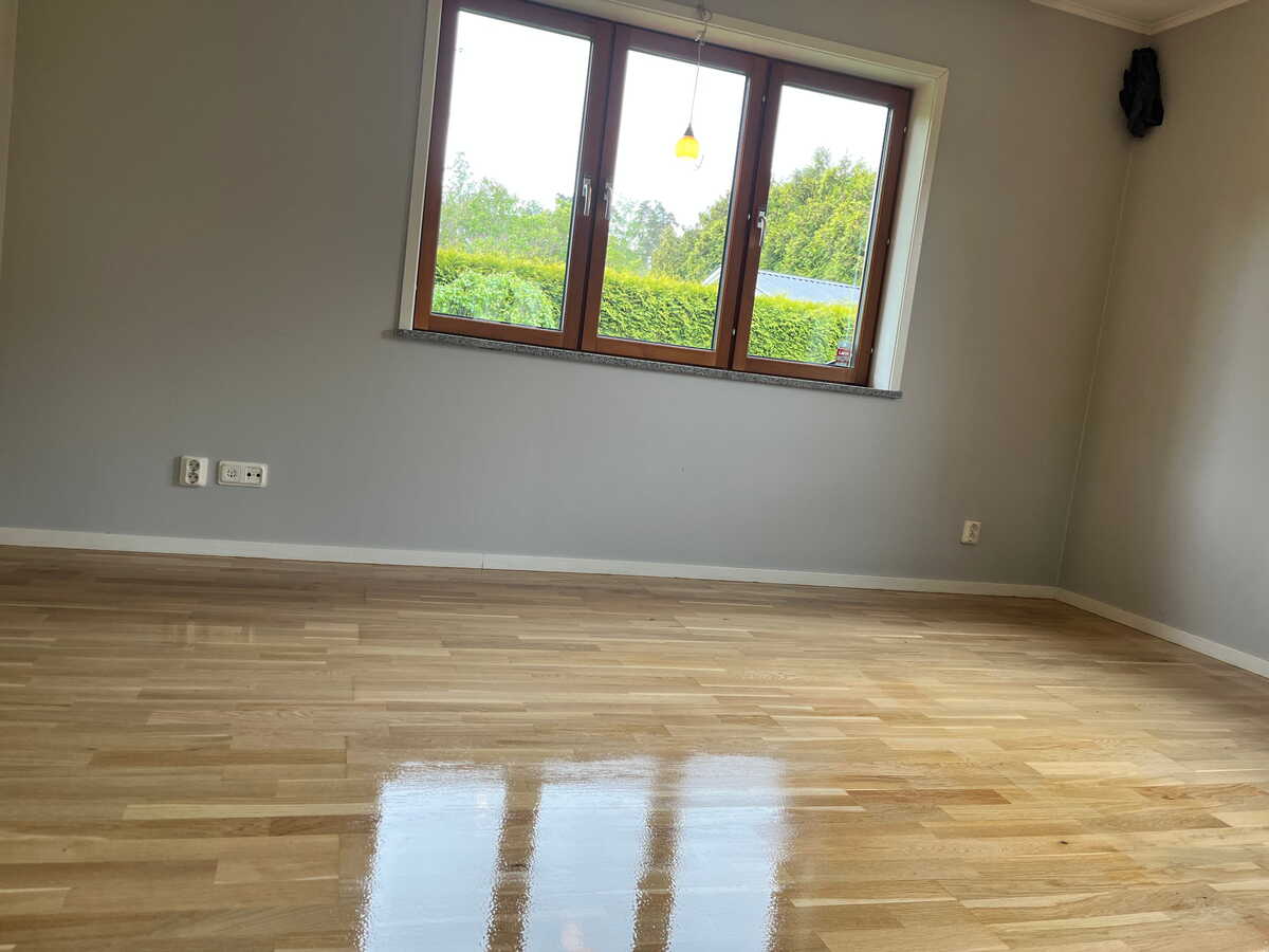 Vardagsrum med nylackat trägolv efter golvslipning.