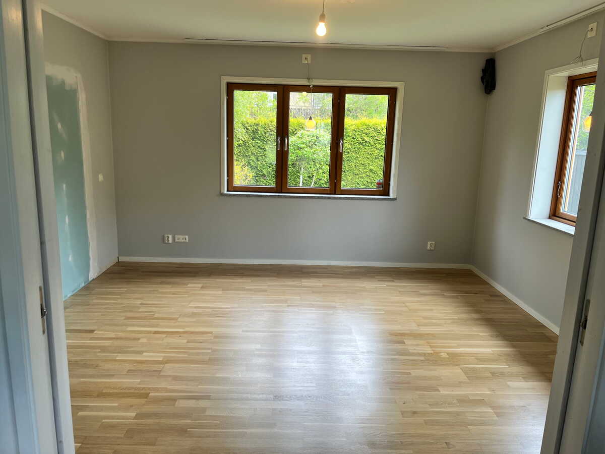 Tomt rum med nyslipat parkettgolv och fönster.
