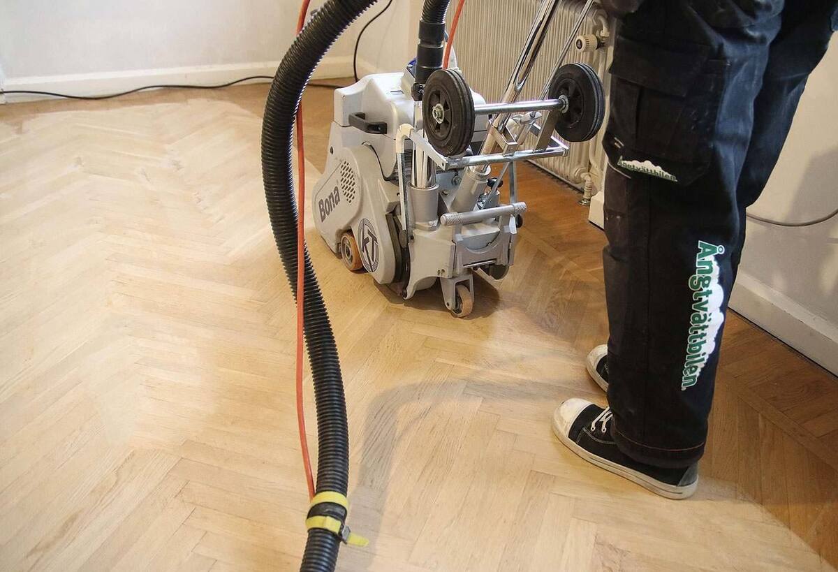 Golvslipning av parkettgolv med slipmaskin i bostad.
