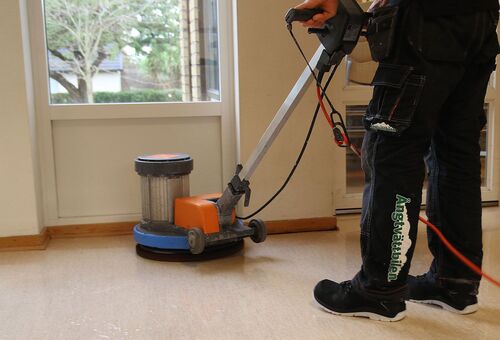 Person som utför golvvård med polermaskin i rum.