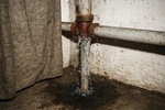 Vattenläcka från rostigt rör i källarutrymme