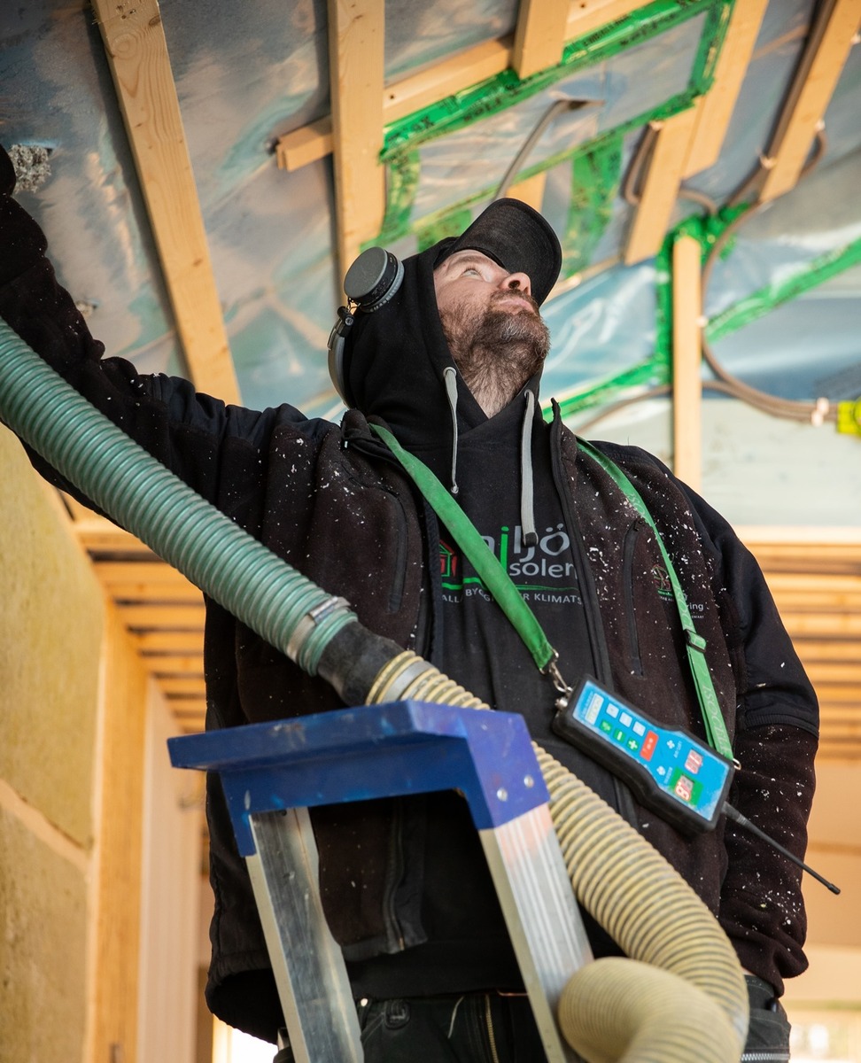 Installatör som blåser in lösullsisolering i vägg under byggnation