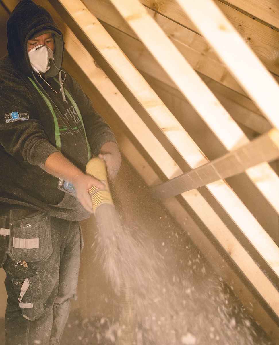 Installatör som blåser lösullsisolering på vind i bostadshus