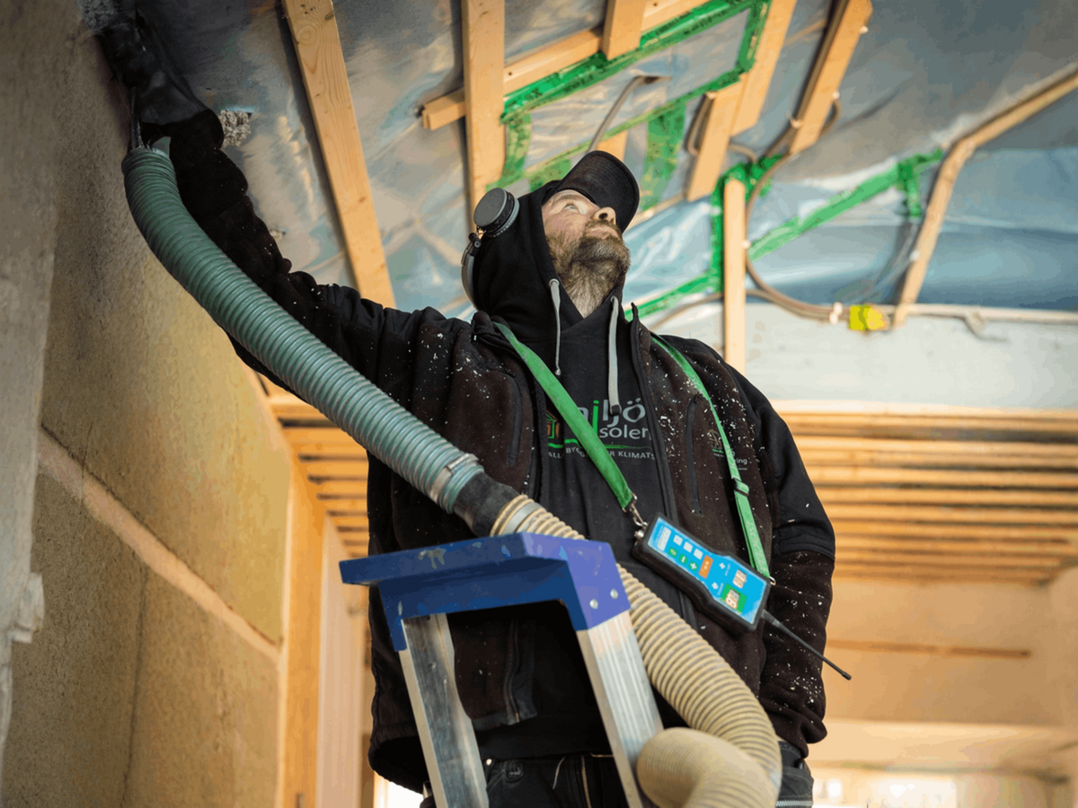Installatör som blåser in lösullsisolering i vägg under byggnation