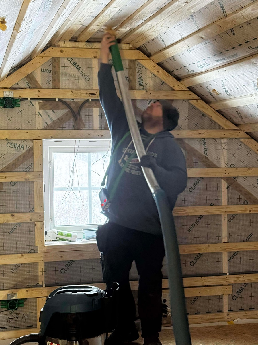 Installatör som blåser in isolering i snedtak på vind