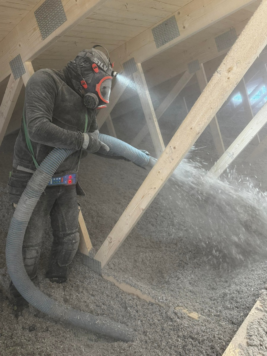 Installatör som sprutar lösullsisolering på vind i hus