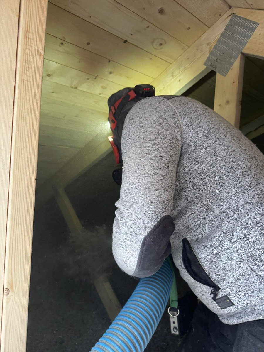 Arbetare som installerar lösullsisolering i snedtak på vind