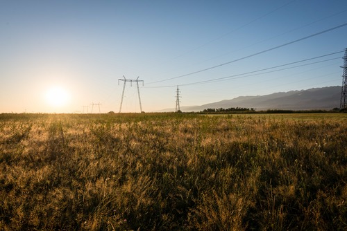Kraftledning över öppet landskap vid solnedgång