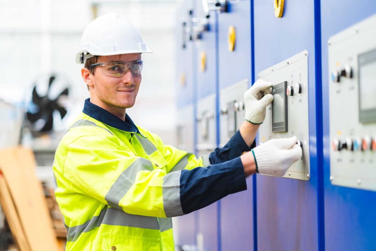 Elektriker arbetar vid elektriskt styrskåp i industriell anläggning