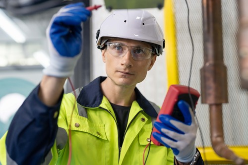 Tekniker i skyddsutrustning mäter elektrisk installation