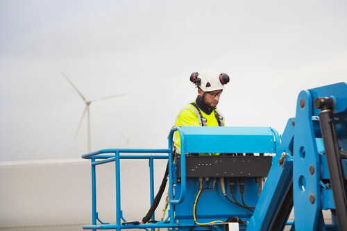 Tekniker arbetar på lyftplattform vid vindkraftverk