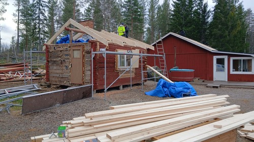 Hus under byggnation med trästomme och byggmaterial