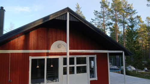 Framsida av rött hus med nytt tak i träområde