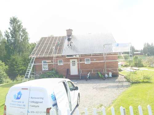 Hus där taket renoveras med arbetsbil på uppfarten